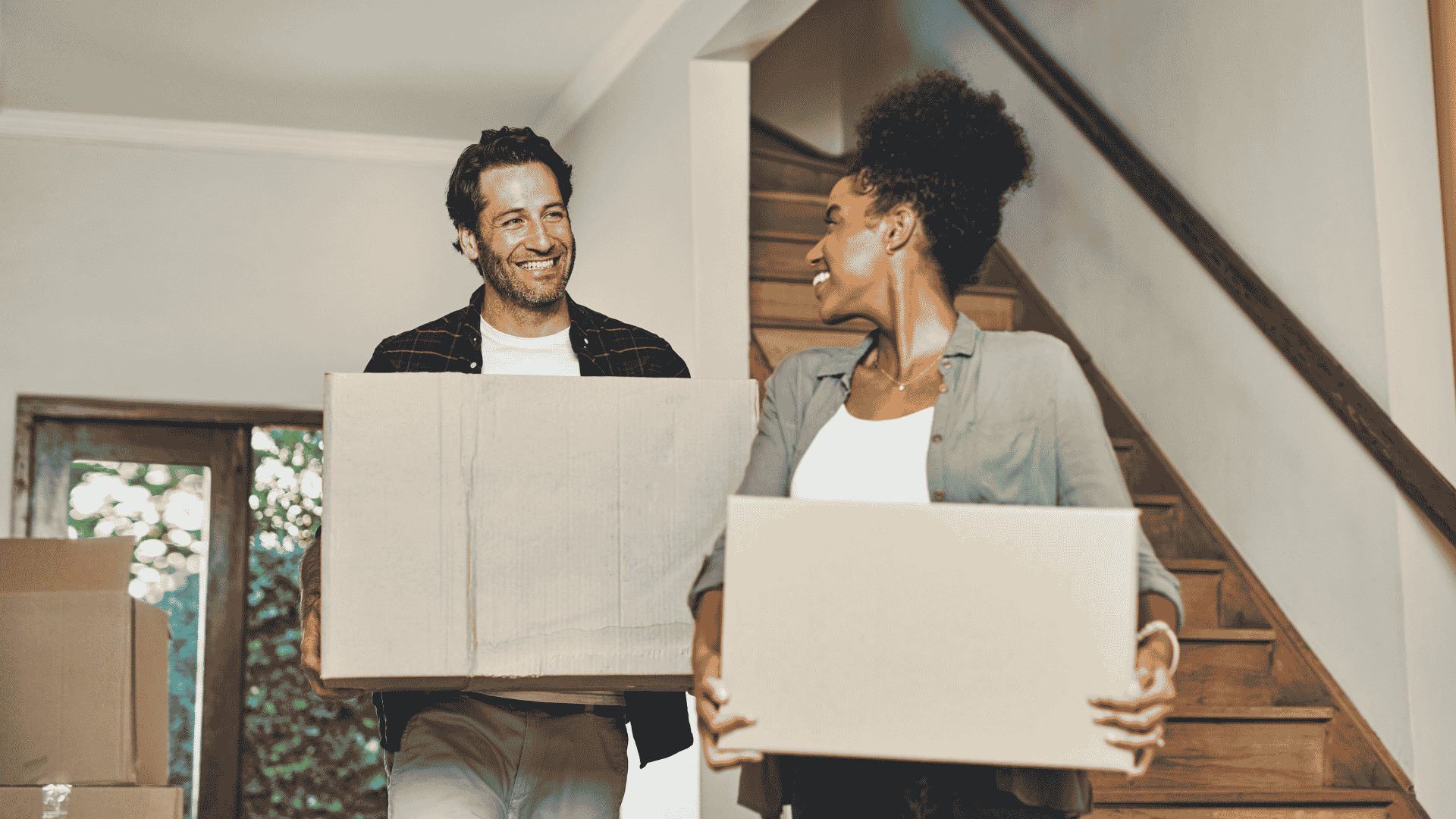 Deux personnes avec des cartons dans un logement, illustrant un déménagement et la gestion des documents liés à la location.